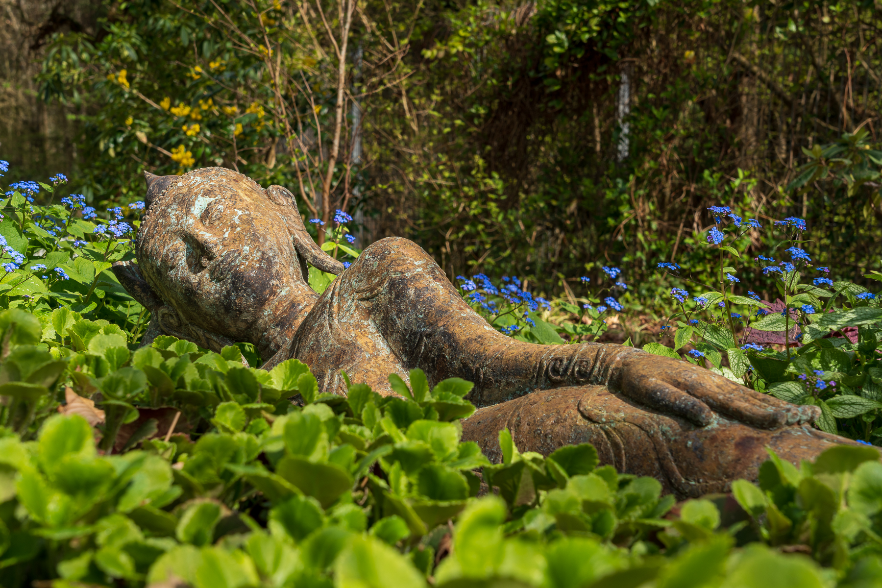 Statue eines liegenden Buddhas in einer Blumenwiese im Nepal Himalaya Park Wiesent