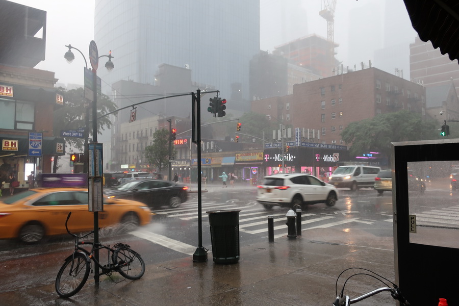 Verregnete Straßen in New York. Autos fahren durch den Regen im Vordergrund fährt ein gelbes Taxi